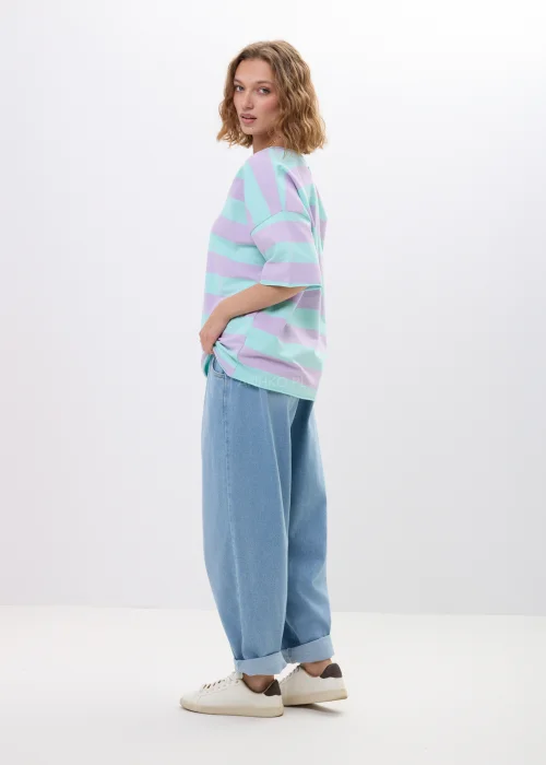 Jasne jeansy damskie o luźnym fasonie baggy z elastyczną gumką w pasie. Model z podwiniętymi nogawkami i miękkim denimem zapewnia wygodę oraz swobodny, miejski charakter stylizacji.