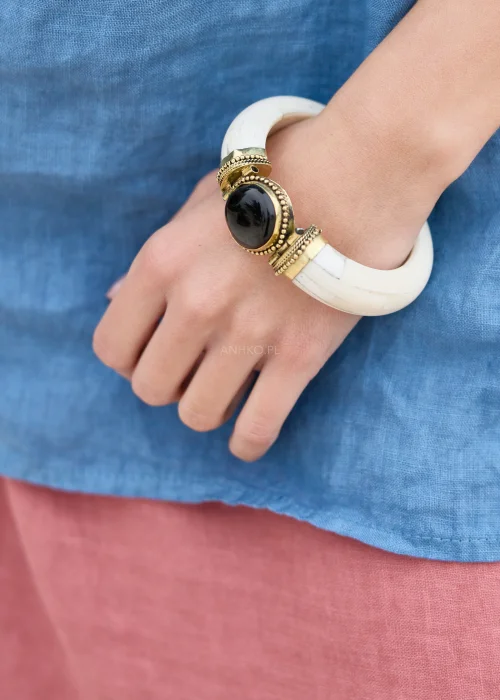 Biała bransoletka z ozdobnym czarnym kamieniem i złotymi detalami. Wyrazisty dodatek w stylu boho, który przyciąga uwagę eleganckim kontrastem kolorów.
