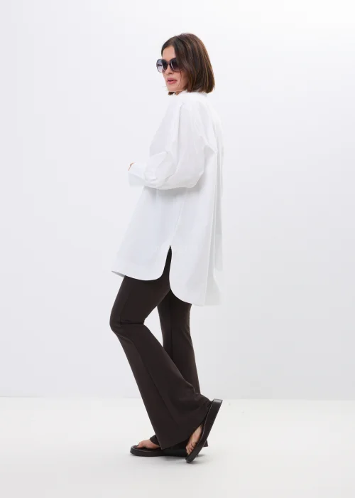Biała koszula damska oversize z szerokim kołnierzem i efektownymi bufiastymi rękawami. Elegancki, wydłużony fason w minimalistycznym stylu.