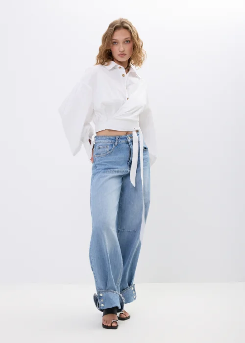 Spodnie jeansowe wide leg w jasnoniebieskim odcieniu z efektownymi mankietami zapinanymi na napy. Szerokie nogawki i nowoczesne detale nadają modelowi modny, swobodny charakter.