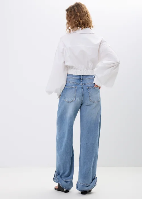 Spodnie jeansowe wide leg w jasnoniebieskim odcieniu z efektownymi mankietami zapinanymi na napy. Szerokie nogawki i nowoczesne detale nadają modelowi modny, swobodny charakter.