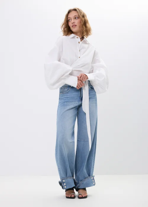 Spodnie jeansowe wide leg w jasnoniebieskim odcieniu z efektownymi mankietami zapinanymi na napy. Szerokie nogawki i nowoczesne detale nadają modelowi modny, swobodny charakter.