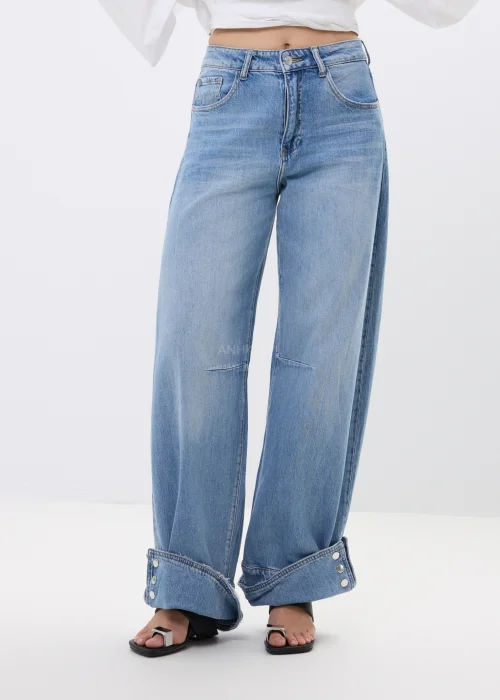 Spodnie jeansowe wide leg w jasnoniebieskim odcieniu z efektownymi mankietami zapinanymi na napy. Szerokie nogawki i nowoczesne detale nadają modelowi modny, swobodny charakter.