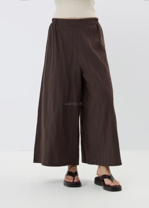 Spodnie damskie culotte w kolorze czekoladowego brązu z subtelnym prążkowanym wzorem. Szerokie nogawki i luźny fason zapewniają komfort oraz elegancki wygląd.