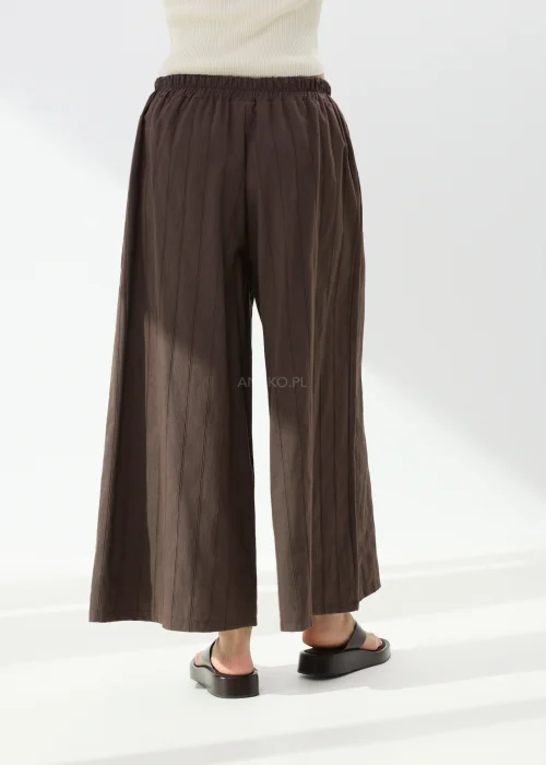 Spodnie damskie culotte w kolorze czekoladowego brązu z subtelnym prążkowanym wzorem. Szerokie nogawki i luźny fason zapewniają komfort oraz elegancki wygląd.