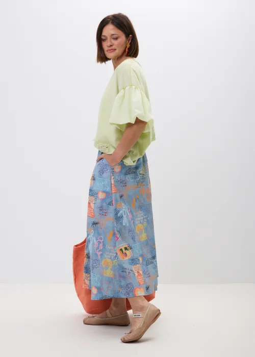 Rozkloszowana spódnica maxi w niebieskim kolorze z artystycznym printem, napisami i kolorowymi grafikami. Zwiewny fason oraz szeroki krój nadają stylizacji oryginalnego, miejskiego charakteru.