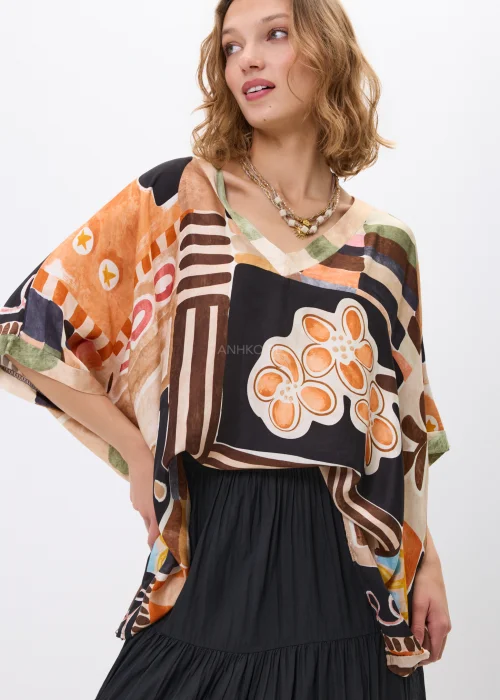 Wzorzysta bluzka oversize w geometryczny print w odcieniach beżu, czerni i pomarańczu, z luźnym rękawem, stylizowana w komplecie ze spódnicą w artystycznym looku.