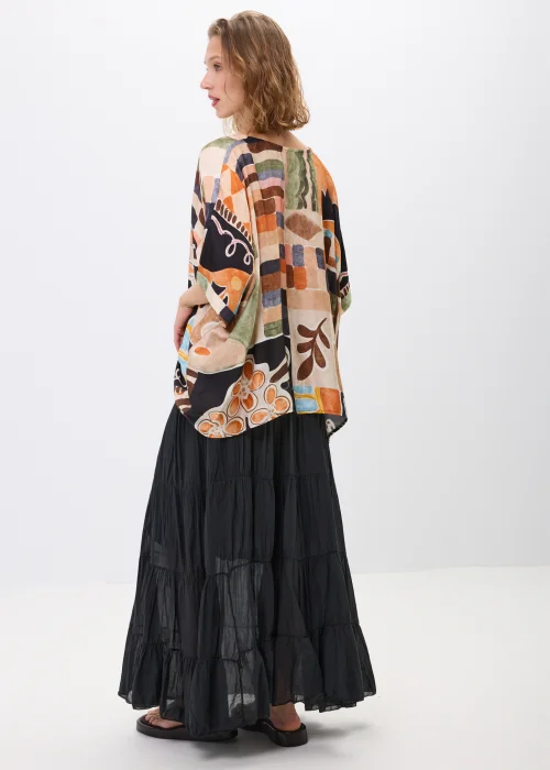 Wzorzysta bluzka oversize w geometryczny print w odcieniach beżu, czerni i pomarańczu, z luźnym rękawem, stylizowana w komplecie ze spódnicą w artystycznym looku.