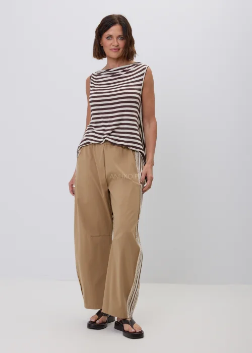 Damski top bez rękawów w beżowo-brązowe paski o luźnym, asymetrycznym fasonie. Modna stylizacja casual ze spodniami w kolorze camel z ozdobnym koronkowym lampasem, inspirowana naturalną elegancją.