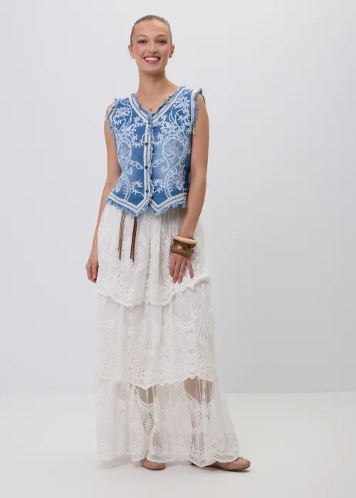 Biała koronkowa spódnica maxi w stylu boho z warstwowymi falbanami, ażurowymi haftami i ozdobnym brązowym paskiem w talii. Romantyczny model o efektownym wykończeniu, idealny do letnich i eleganckich stylizacji.