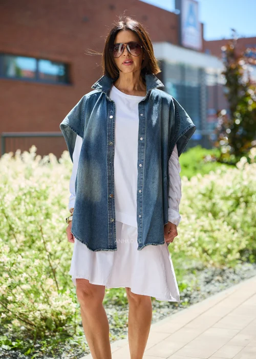 Jeansowa kamizelka oversize damska z efektem sprania, zapinana na napy, z szerokimi rękawami i wysokim kołnierzem. Model stylizowany z białą sukienką, tworzący nowoczesny casualowy look.