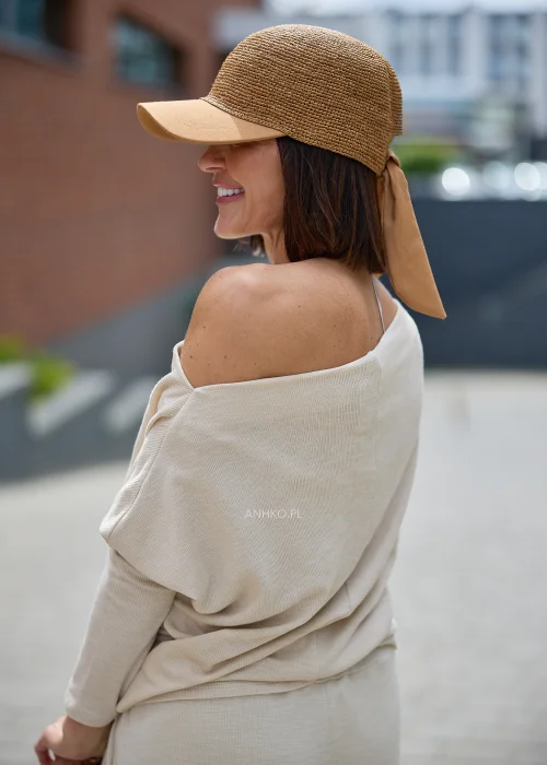 Pleciona czapka z daszkiem w kolorze camel wykonana z naturalnej rafii, ozdobiona dużą kokardą z tyłu, utrzymana w kobiecym stylu boho
