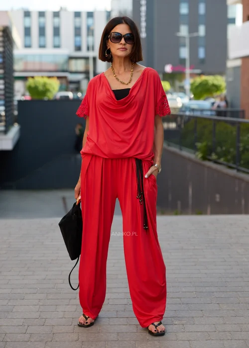 Czerwona bluzka damska oversize z drapowanym dekoltem i ażurowymi rękawami w eleganckiej stylizacji z czerwonymi spodniami