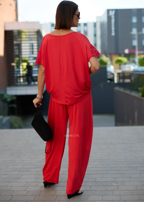 Czerwona bluzka damska oversize z drapowanym dekoltem i ażurowymi rękawami w eleganckiej stylizacji z czerwonymi spodniami