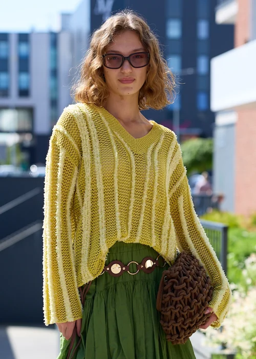 Ażurowy sweter o luźnym fasonie oversize z dekoltem w serek (V) oraz długimi rękawami. Model wykonany z lekkiego, dekoracyjnego splotu z pionowymi, wypukłymi pasami, zakończony ściągaczami przy dekolcie