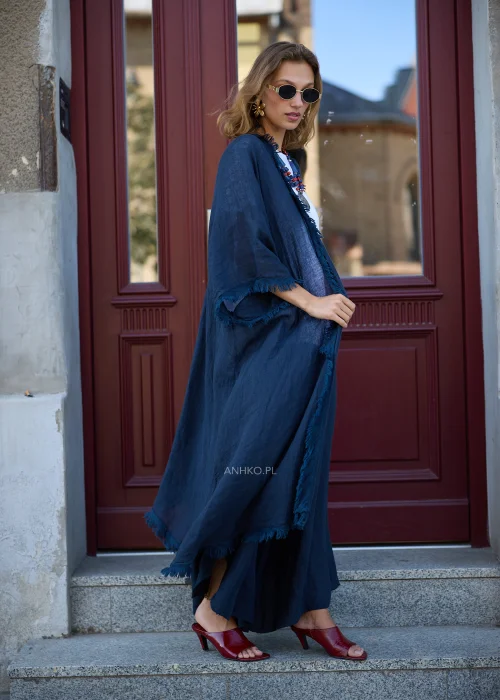 Granatowe lniane kimono damskie z szerokimi rękawami i surowym wykończeniem, narzucone na białą bluzkę i szerokie spodnie w eleganckiej stylizacji