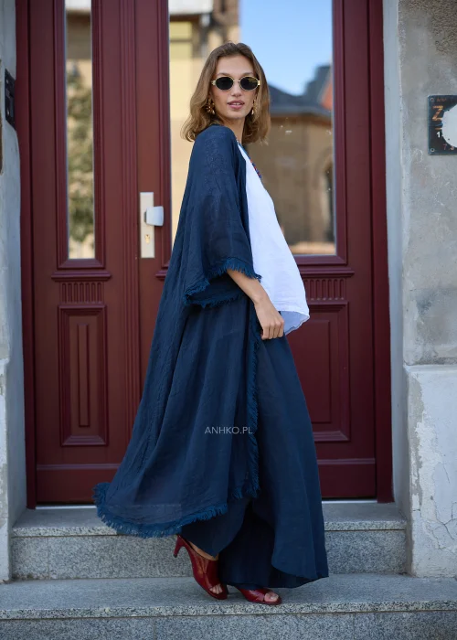 Granatowe lniane kimono damskie z szerokimi rękawami i surowym wykończeniem, narzucone na białą bluzkę i szerokie spodnie w eleganckiej stylizacji