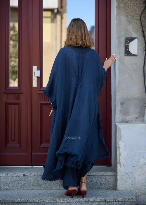 Granatowe lniane kimono damskie z szerokimi rękawami i surowym wykończeniem, narzucone na białą bluzkę i szerokie spodnie w eleganckiej stylizacji