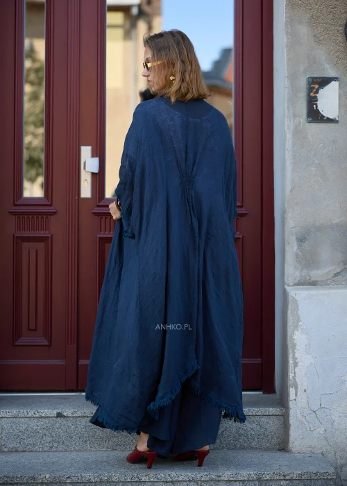 Granatowe lniane kimono damskie z szerokimi rękawami i surowym wykończeniem, narzucone na białą bluzkę i szerokie spodnie w eleganckiej stylizacji