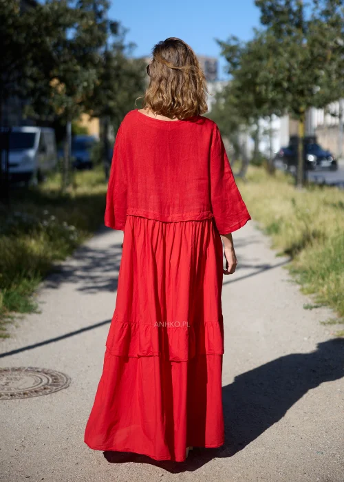 Sukienka maxi z szerokim, półokrągłym dekoltem, rękawami o długości 3/4, odcięciem pod biustem oraz dwiema szerokimi falbanami u dołu. Model posiada luźny fason oversize i praktyczne kieszenie po bokach.