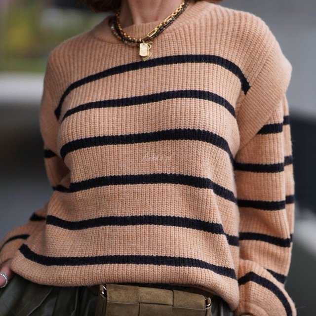 Beżowy sweter oversize w czarne pasy z grubej dzianiny, luźny krój i długie rękawy w modzie damskiej