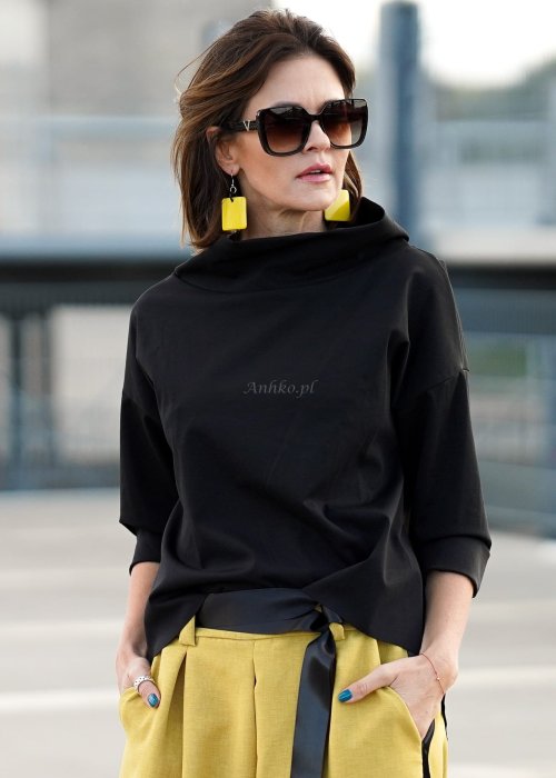 Czarna bluzka oversize z półgolfem i rękawem 3/4, stylizowana z szerokimi spodniami w kontrastowym kolorze w miejskim looku.