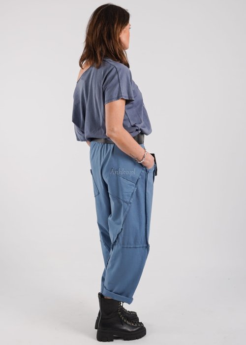 Jasnoniebieskie spodnie dresowe damskie o luźnym kroju z gumką w pasie i ozdobnymi przeszyciami, stylizowane z czarnym t-shirtem i botkami.